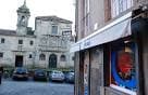Fachada de A Reixa Tenda con toldo y vista de un edificio histórico al fondo en Santiago de Compostela