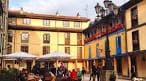 Terraza de un café en la Plaza del Fontán con edificios de fachada amarilla.