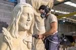 Escultor trabajando en una gran pieza de piedra en el taller de cantería.