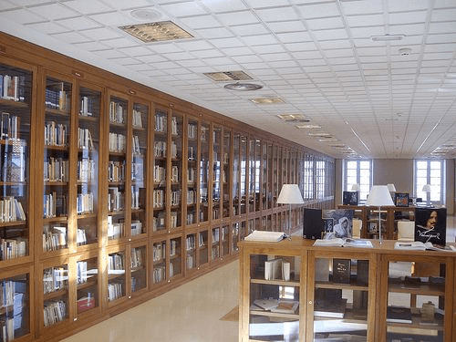 Interior de la biblioteca con estanterías de madera y mesas de estudio
