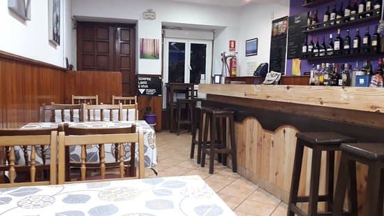 Interior de un restaurante con mesas, sillas y barra de bar