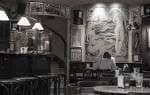 Interior en blanco y negro del café con un gran mural y un cliente