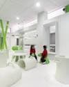 Área de juegos infantil con mobiliario blanco y elementos verdes