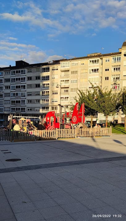 Vista del parque infantil en la Praza de Bretaña con edificios residenciales al fondo.