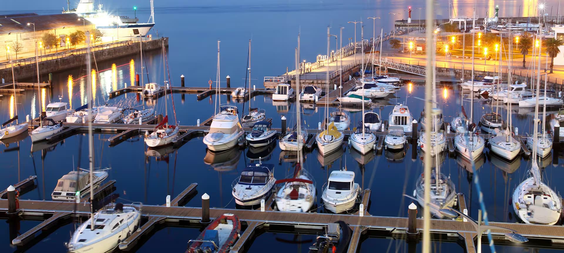 Marina de Vigo con yates y edificios iluminados al atardecer