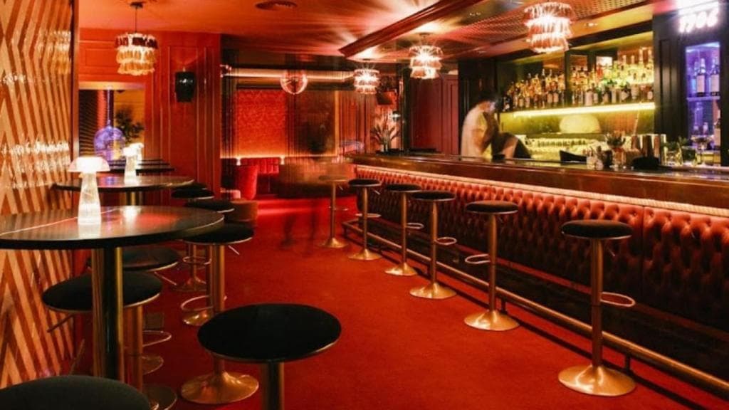 Interior de Don Giorgio con barra de bar y mesas iluminadas en tonos rojos