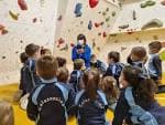 Niños en clase de escalada en un rocódromo interior con un instructor
