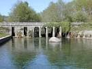 Puente de arcos sobre el río Almofrei en un día soleado