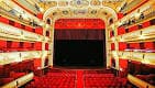 Interior del teatro desde las butacas, mostrando el escenario y los palcos laterales