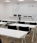 Sala de reuniones o formación con mesas y sillas dispuestas para un evento