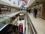 Pasillo interior del Centro Comercial Cuatro Caminos con tiendas y escaleras mecánicas