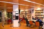 Zona de lectura de la Biblioteca Municipal Sagrada Familia con estanterías y usuarios