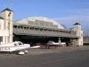 Gran hangar del aeródromo con aviones estacionados en el exterior