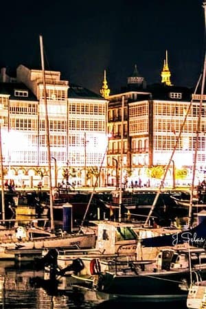 Vista nocturna del Puerto de Curuxeiras con edificios iluminados y barcos amarrados