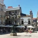 Plaza con edificios históricos y terrazas al aire libre en Vigo, con el cartel 'La Central' visible