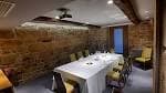 Sala privada con mesa larga para eventos y proyector, paredes de piedra