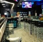 Interior de AD Sports Bar con pantalla grande y barra con taburetes