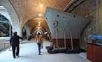 Interior del museo con bóvedas de ladrillo y la proa de un barco en exhibición