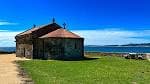 Ermida da Nosa Señora da Alba junto al mar, rodeada de césped verde bajo un cielo azul