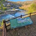 Panel informativo sobre el Camino de Invierno junto a un río y paisaje natural
