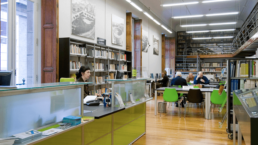 Interior de biblioteca moderna con zonas de lectura y estanterías