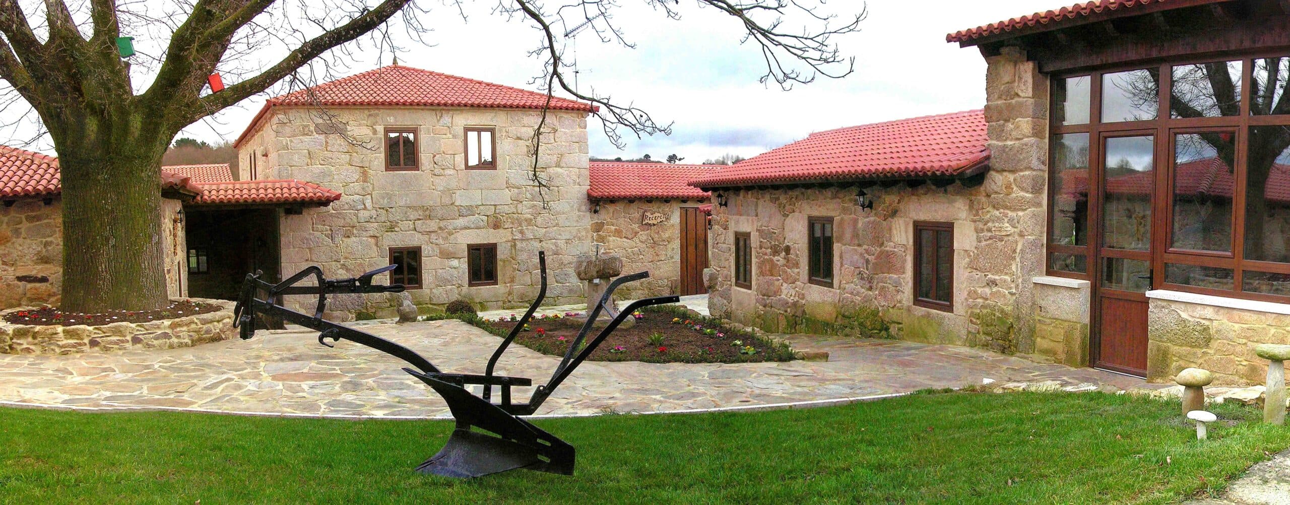 Vista exterior del Pazo de Ludeiro con jardín y elementos rurales